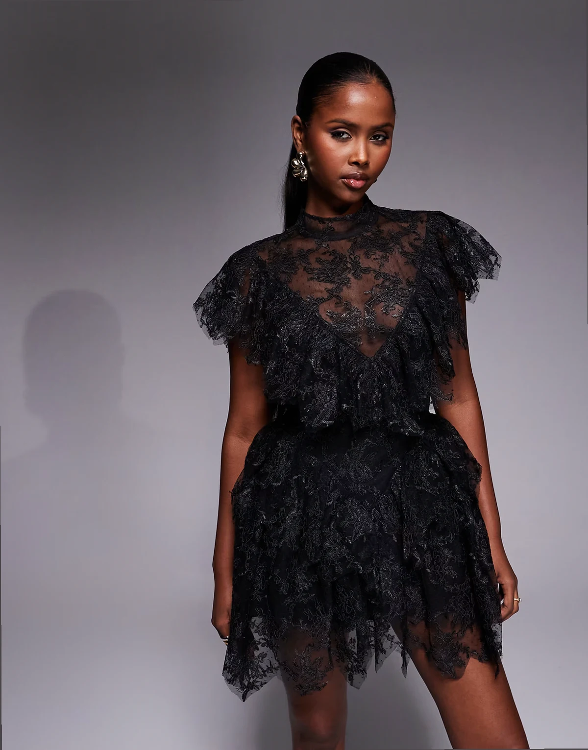 – Tarryn – Czarna koronkowa sukienka mini z zabudowanym dekoltem, falbankami i muszelkowym wykończeniem