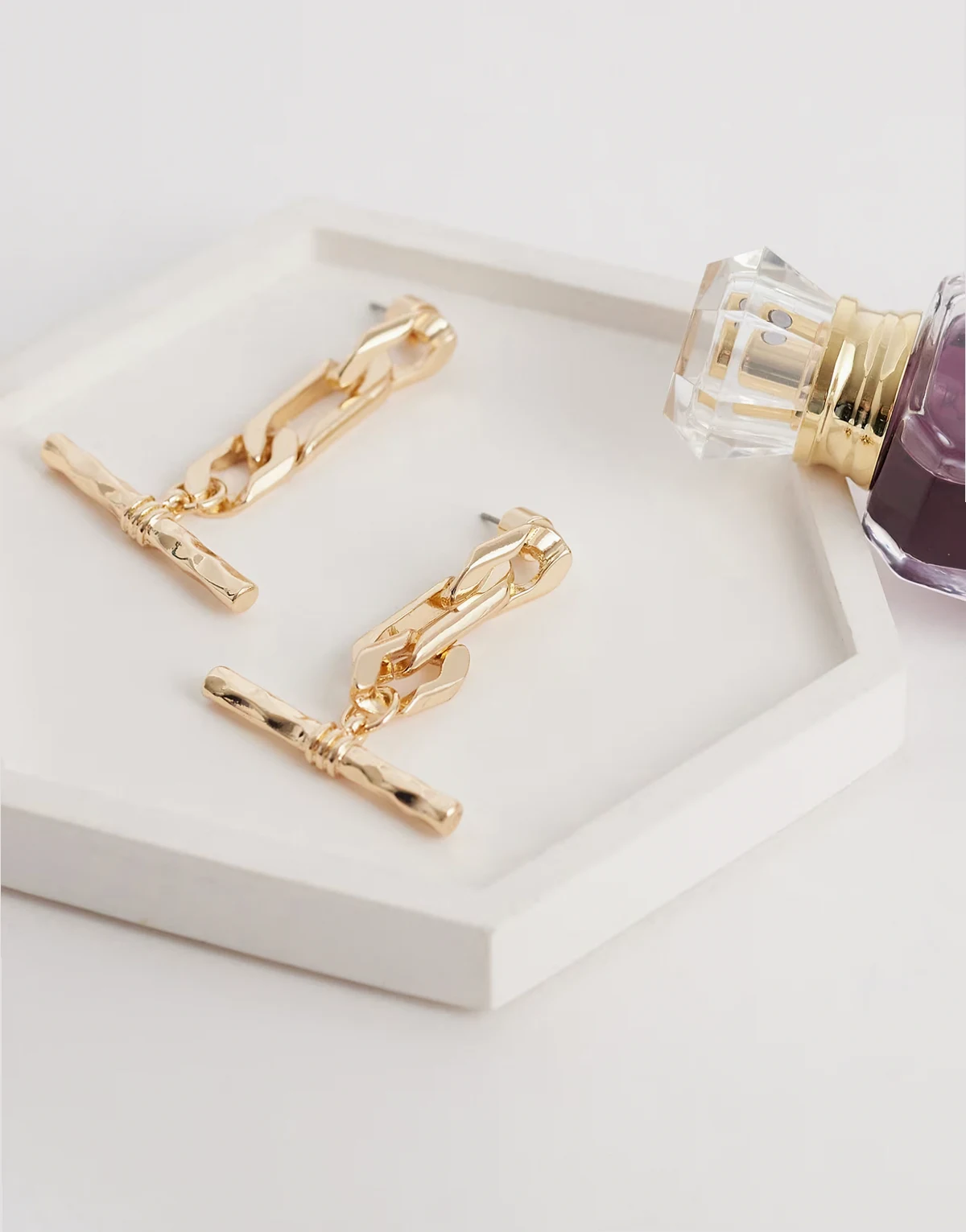 – Kolczyki z zawieszką w kształcie litery T w złotym kolorze