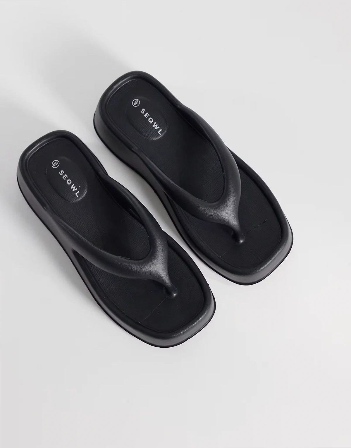 – Czarne sandały na płaskim koturnie z paskiem między palcami