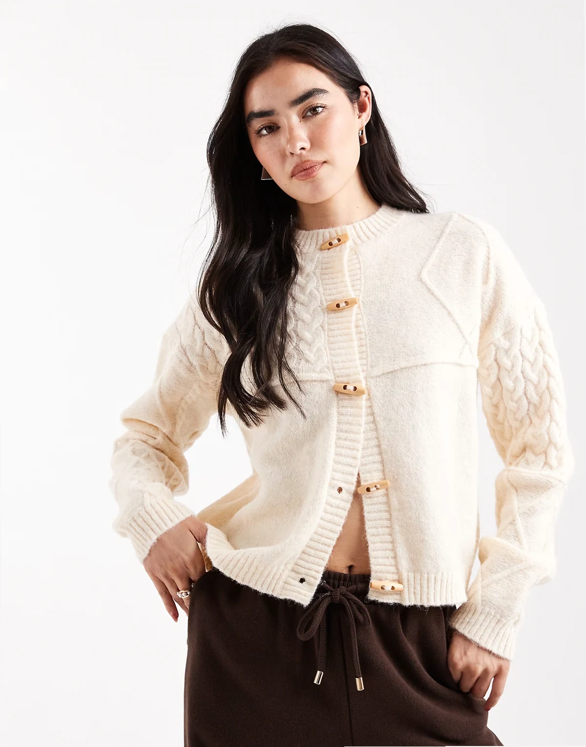 – Zapinany na brązowe guziki kremowy kardigan z dzianiny o warkoczowym splocie