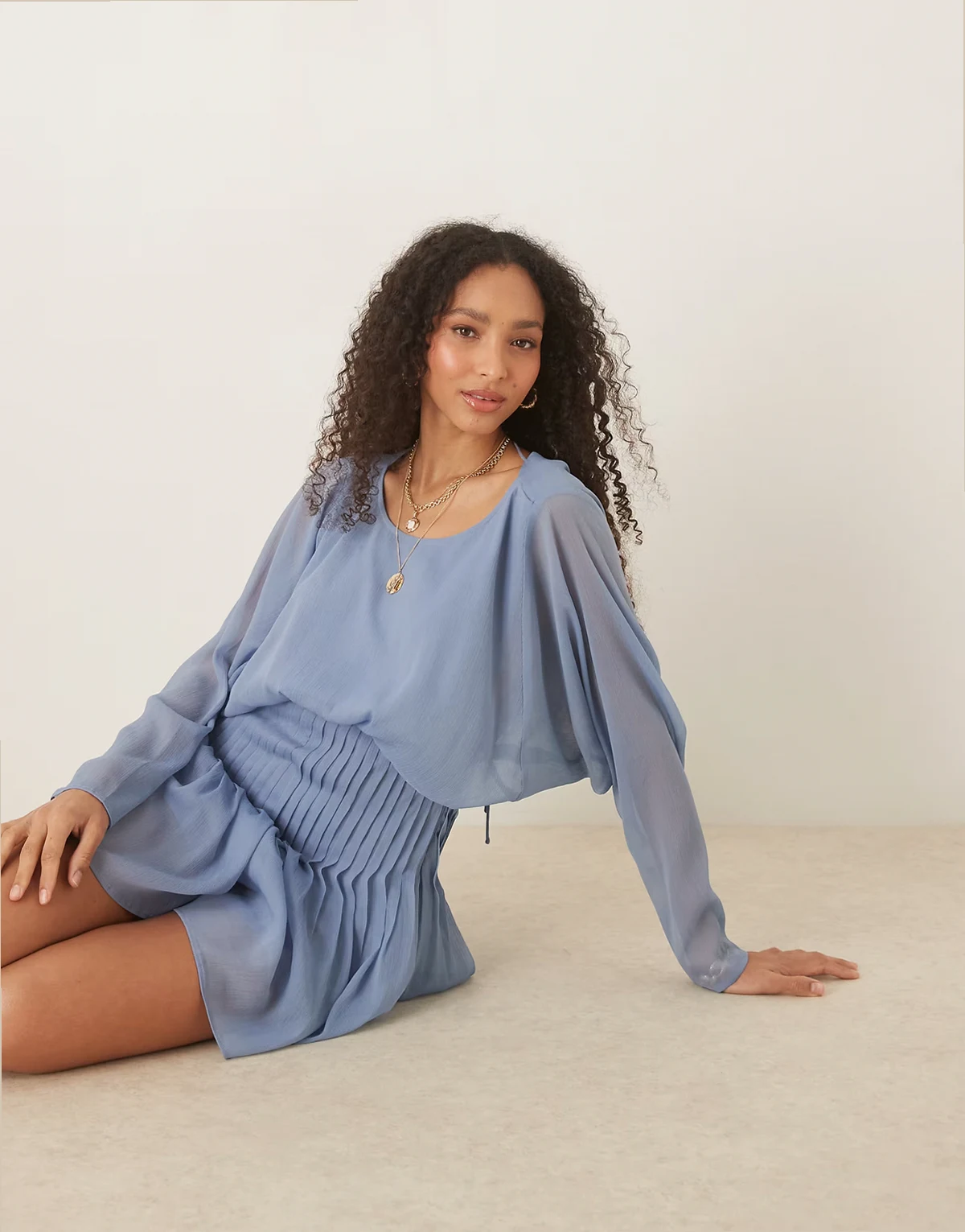 – Krótki kombinezon z plisowanym dołem i drapowanym dekoltem z tyłu, w zgaszonym kolorze niebieskim