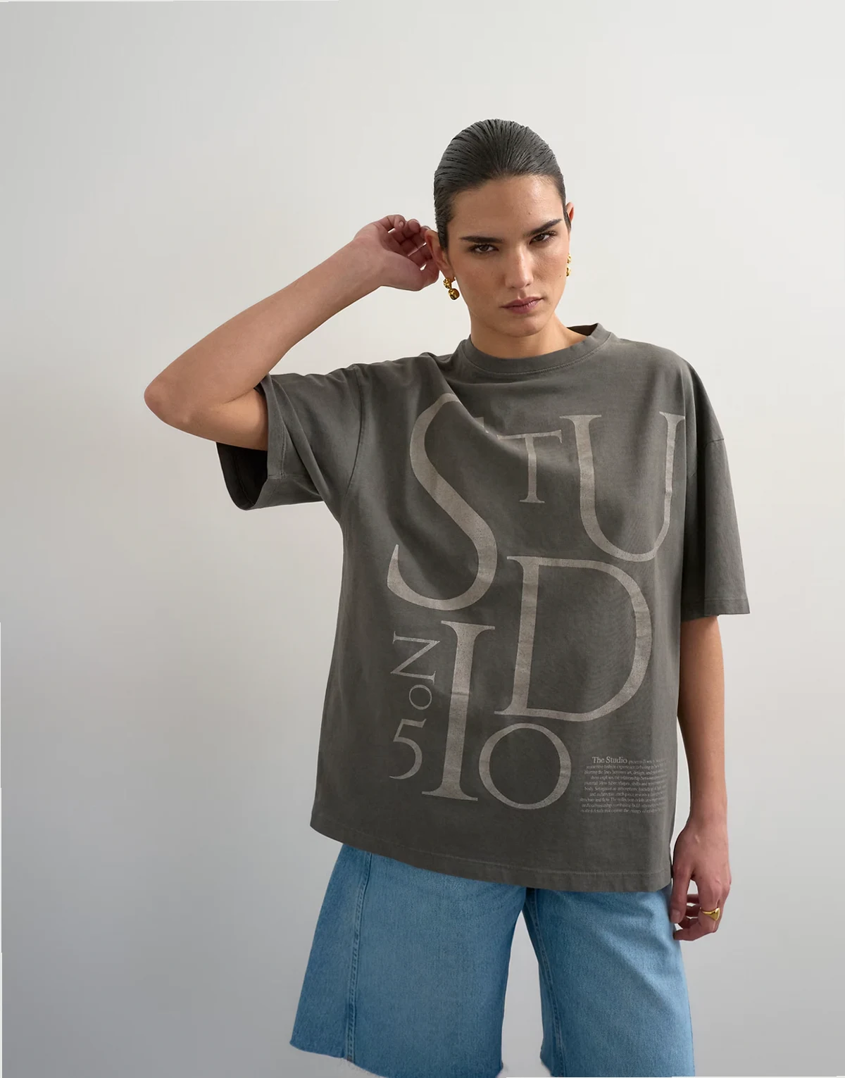 – Czarny sprany T-shirt z obniżoną linią ramion i grafiką „Studio”