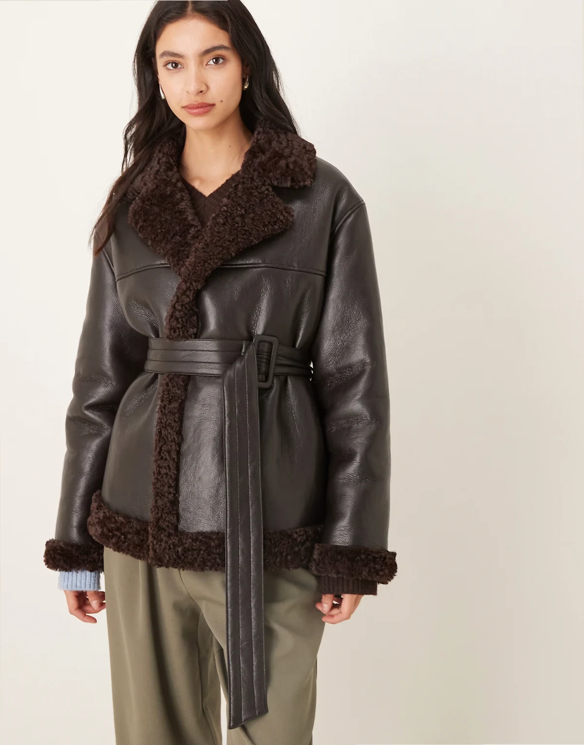 – Kurze Jacke aus Teddy-PU in Schwarz mit Gürtel und braunen Kragenbesätzen