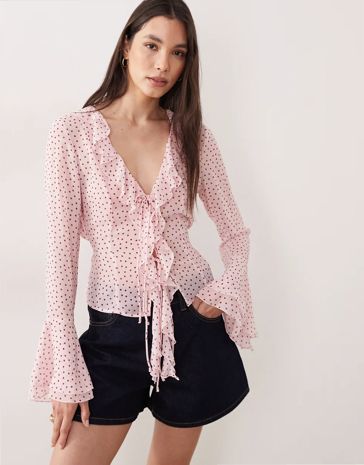 – Różowa bluzka w groszki z falbanką i dekoltem w szpic