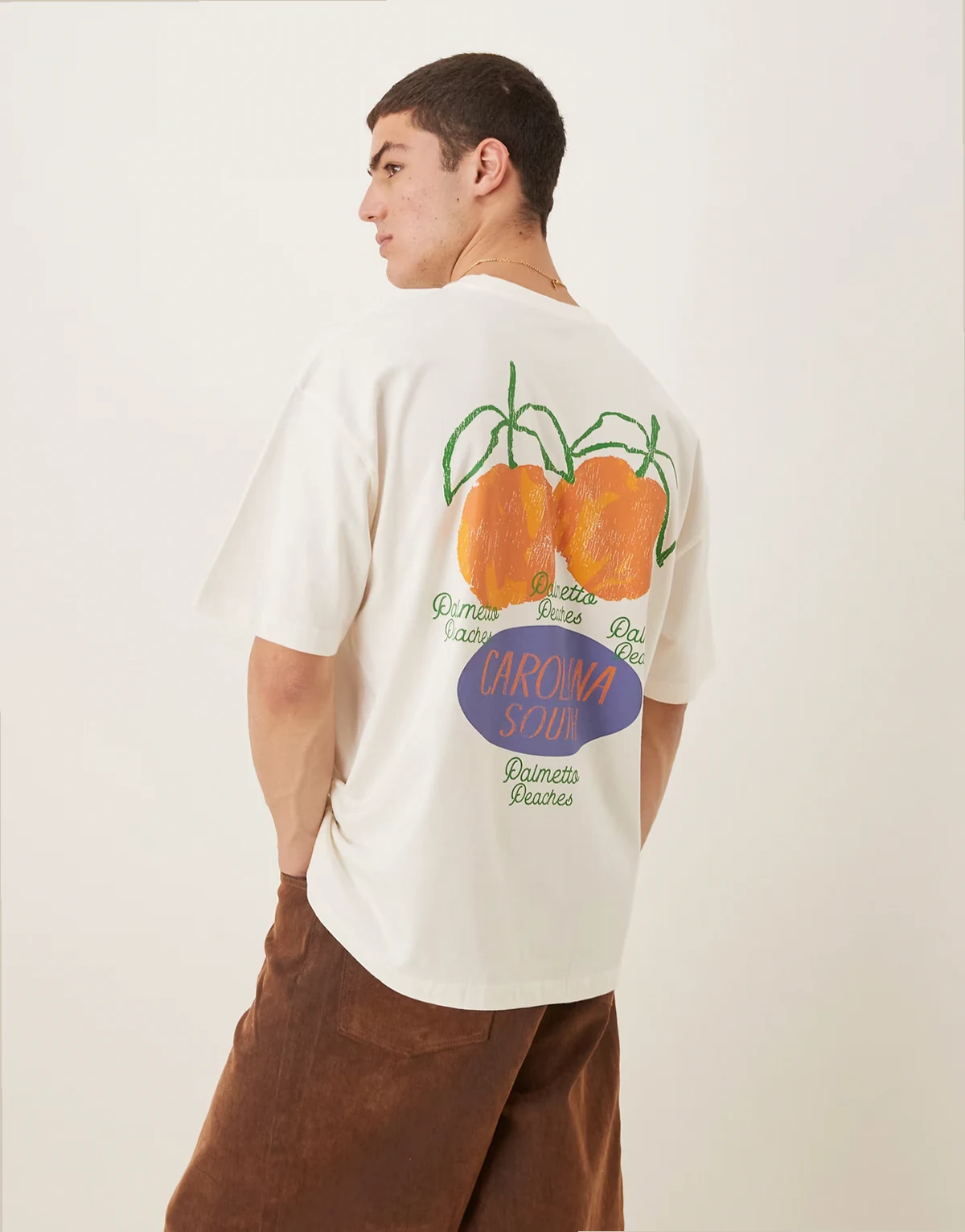 – Kremowy T-shirt oversize z grafiką z brzoskwiniami