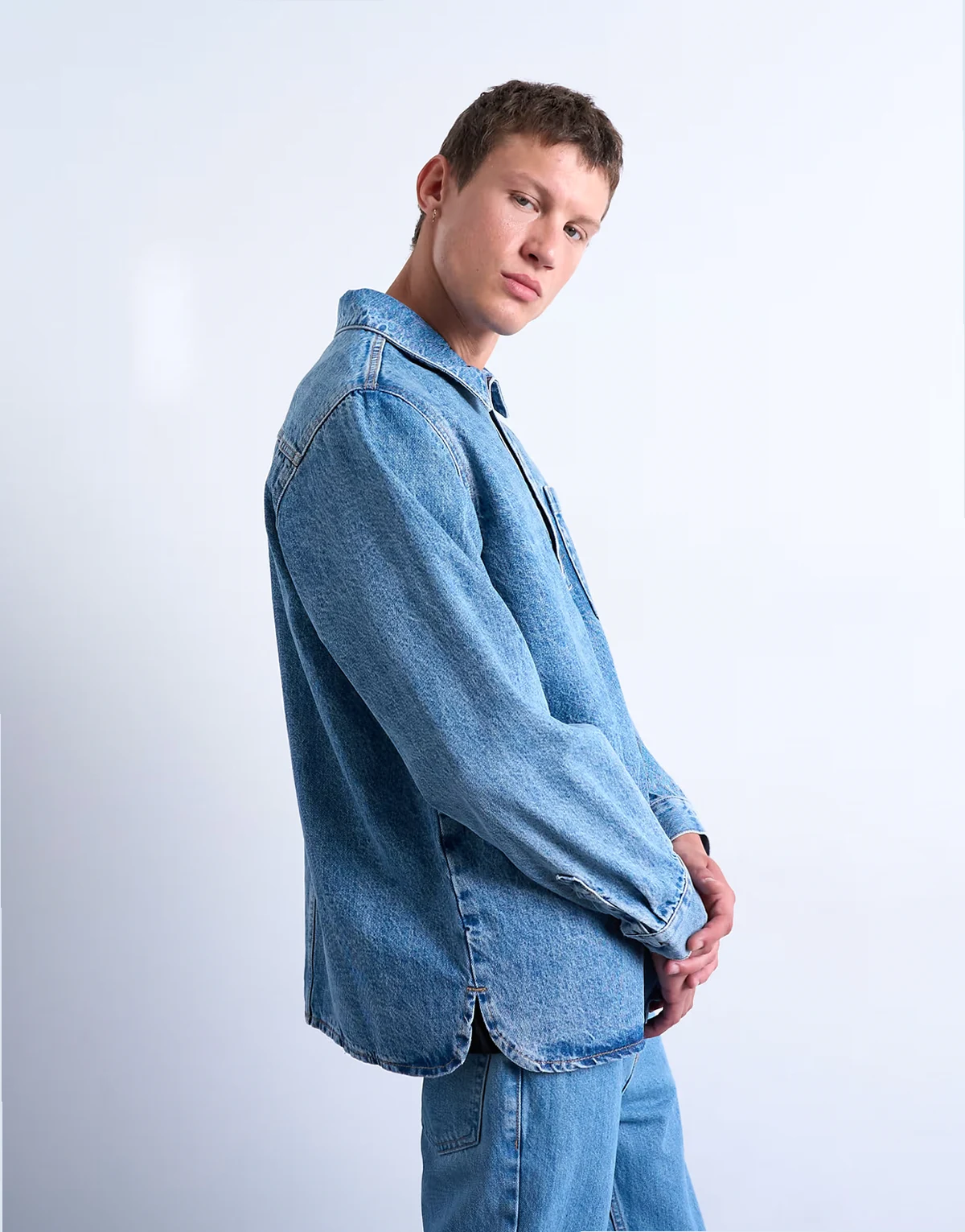 – Niebieska koszula jeansowa o luźnym kroju wkładana przez głowę