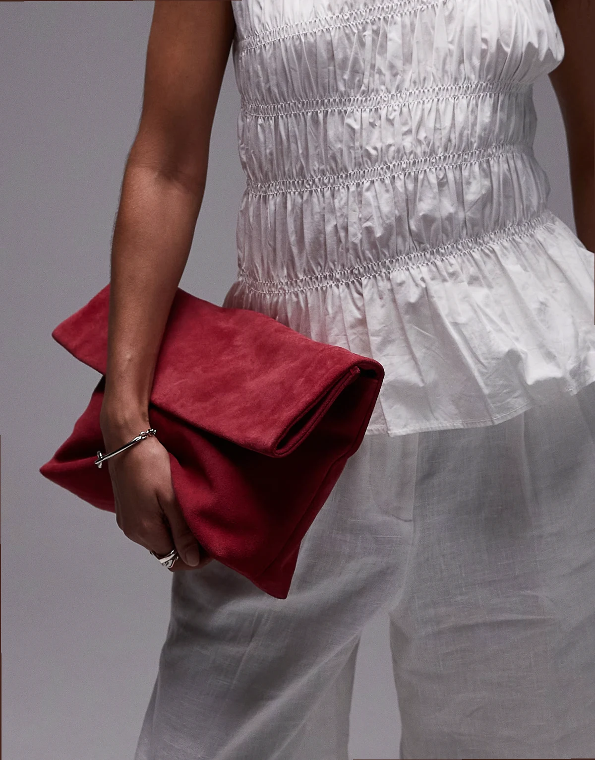 folded suede clutch bag with attachable shoulder strap in red raspberry